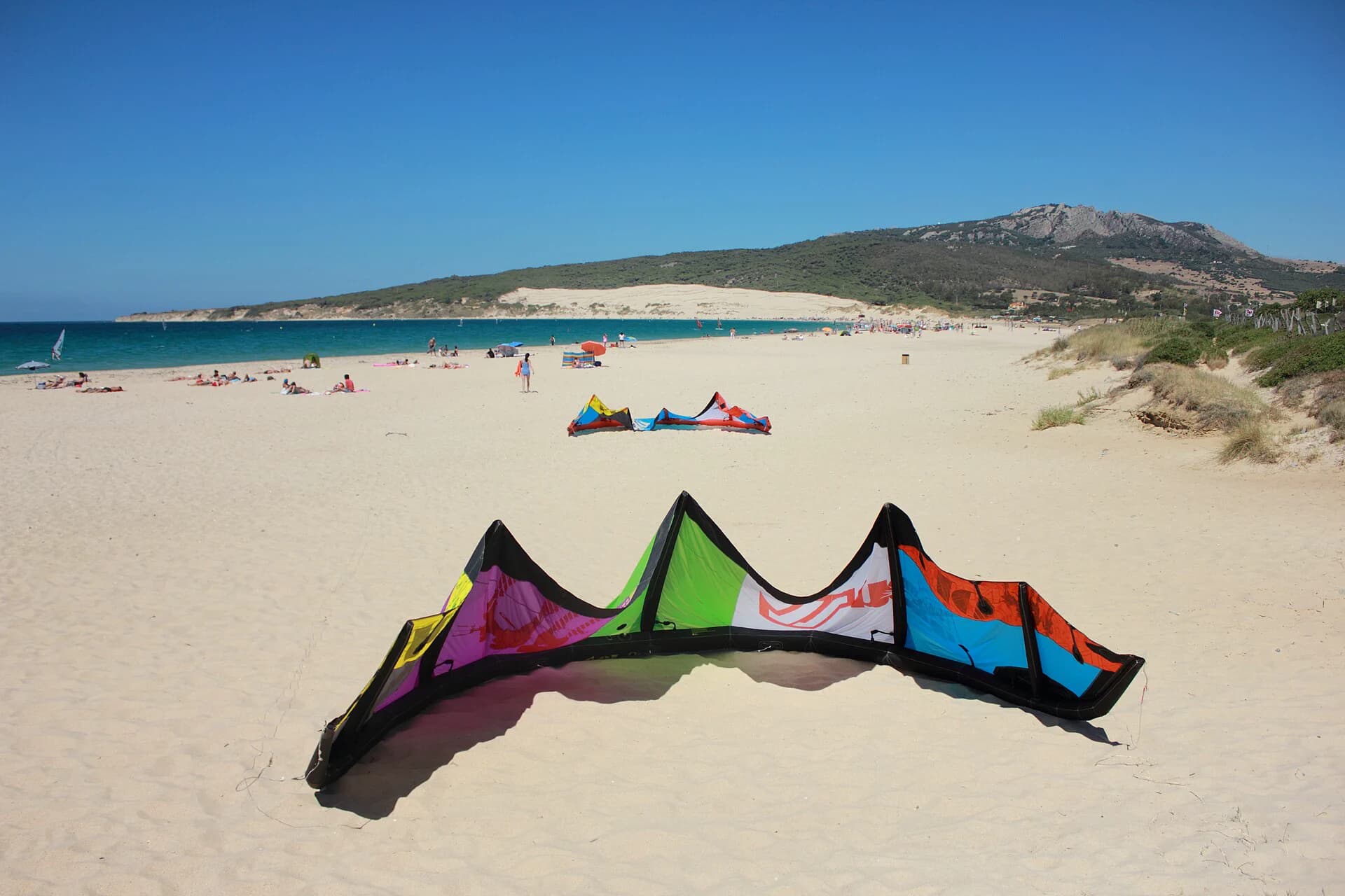 Playa de Valdevaqueros curving towards the Punta Paloma headland, kites on the sand