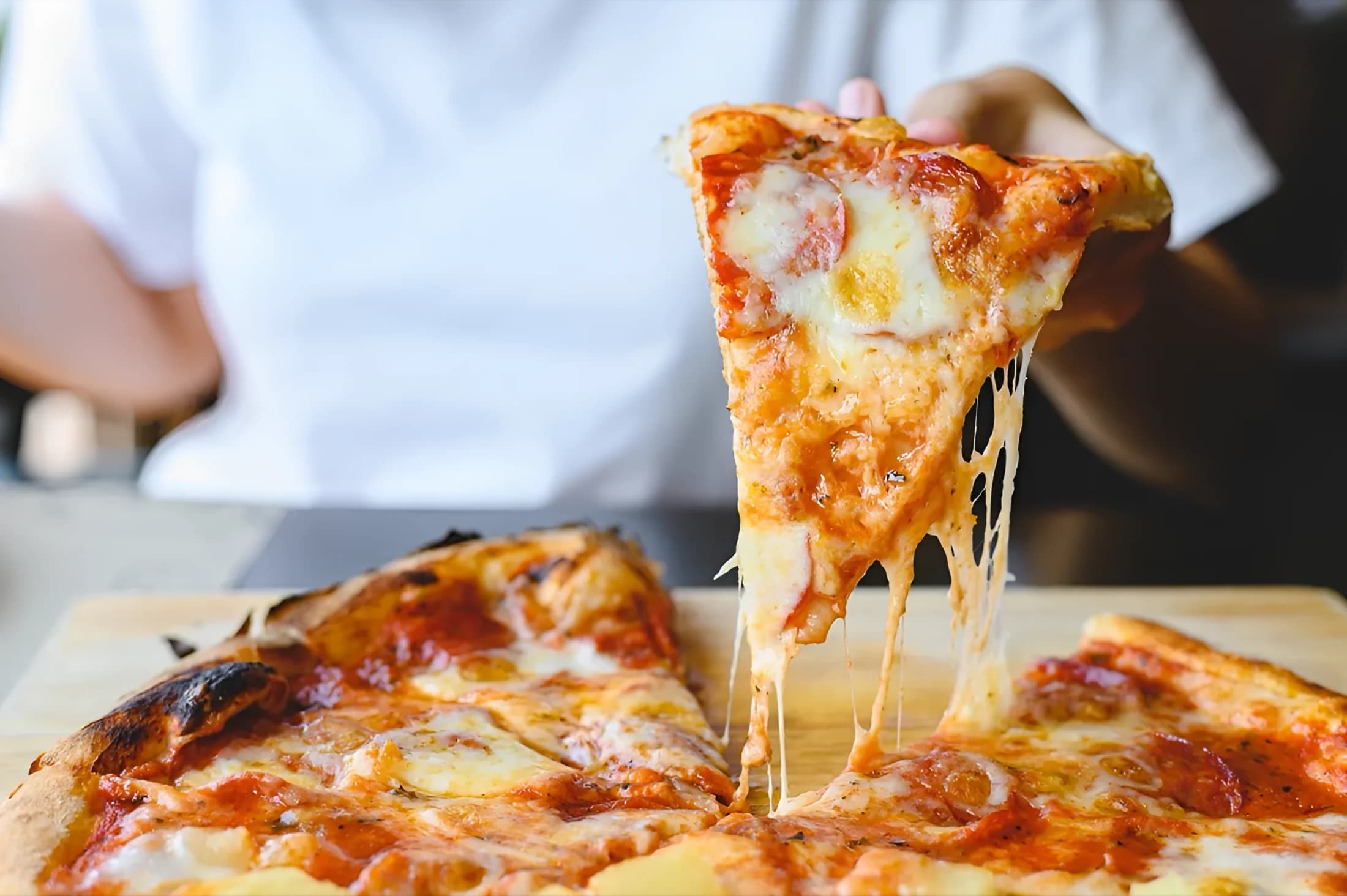 A slice lifted from a wood-fired pizza